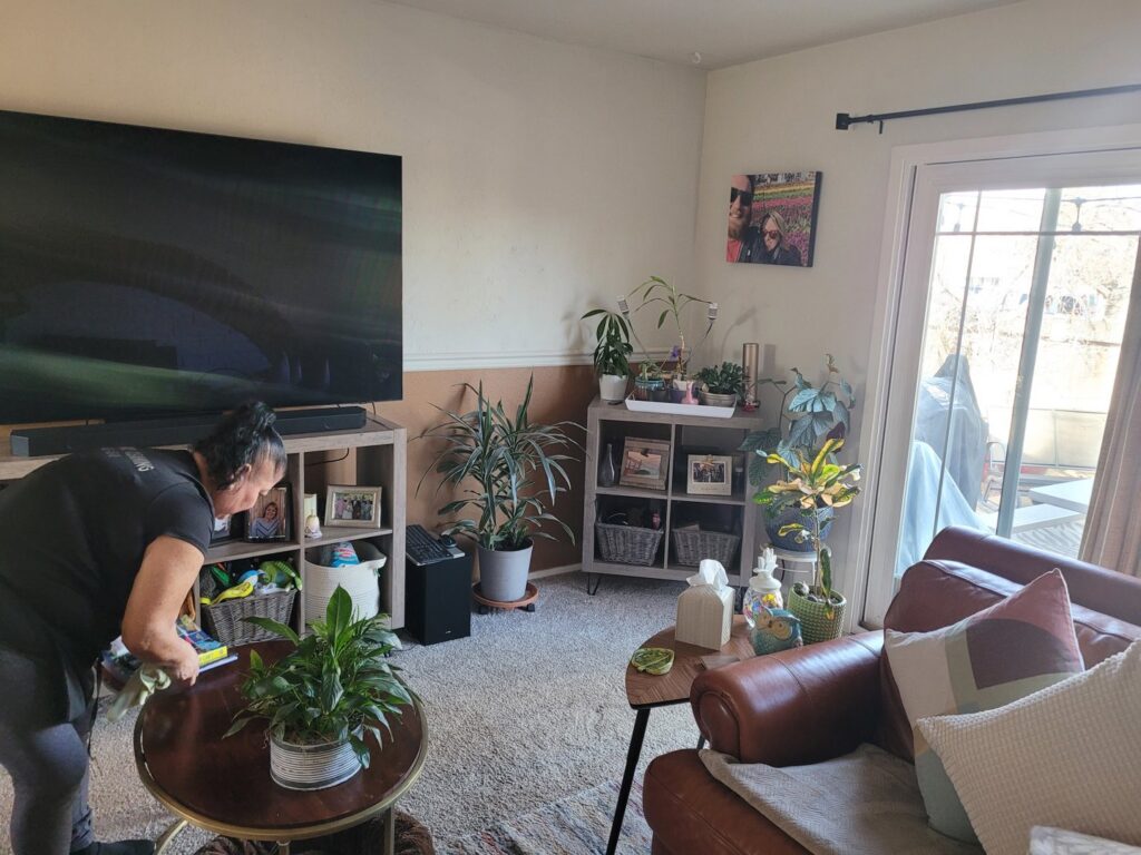 A house cleaner from ECO Friends cleaning service wiping down a coffee table in a cozy living room in Carson City, NV.