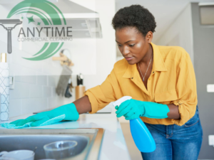 A house cleaner wiping a kitchen countertop with a spray bottle and cloth for Anytime Commercial Cleaning, LLC in Omaha, NE.