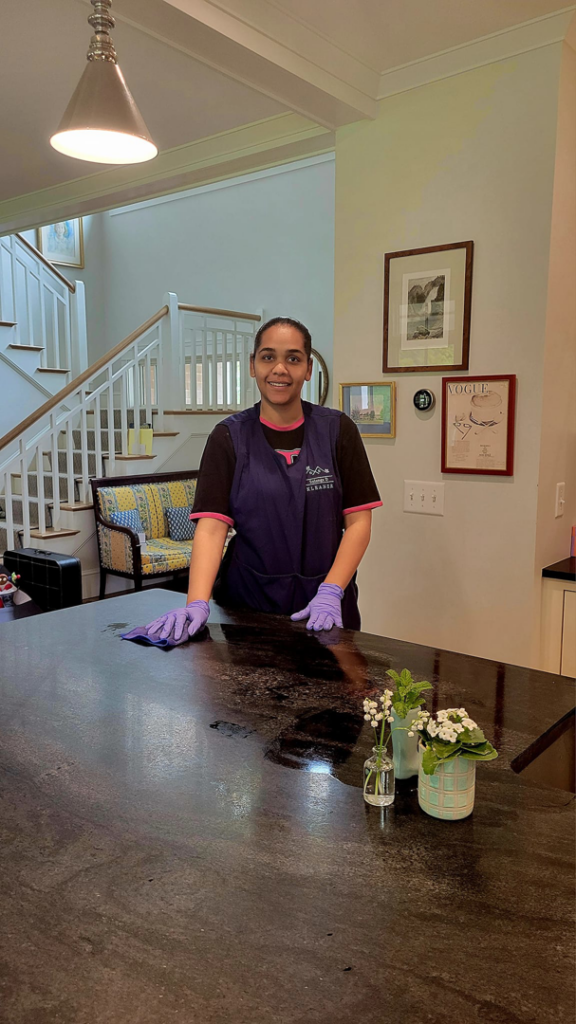 A house cleaner from Solange D Kleaner in New Bedford, MA, wiping down a kitchen counter.