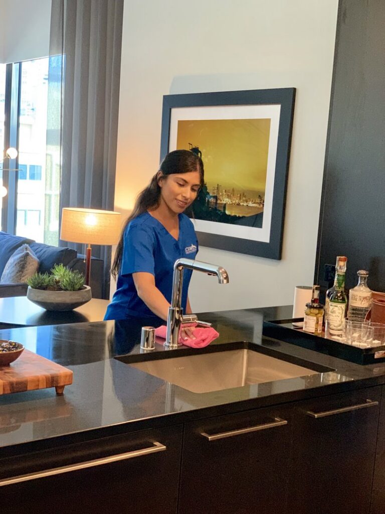 A house cleaner wiping a kitchen sink in a modern home for Crest Cleaning Services in Auburn, WA