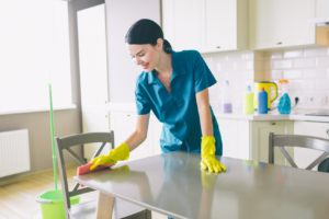 A house cleaner from Days Cleaning wiping down a kitchen table with a sponge in a home in Brockton, MA.