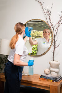 A professional house cleaner from The Cleaning Authority - Bowie, MD, carefully wiping a decorative mirror.