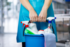 A house cleaner holding a bucket filled with various cleaning supplies for All Advanced Tactical Klean LLC in Columbus, OH.