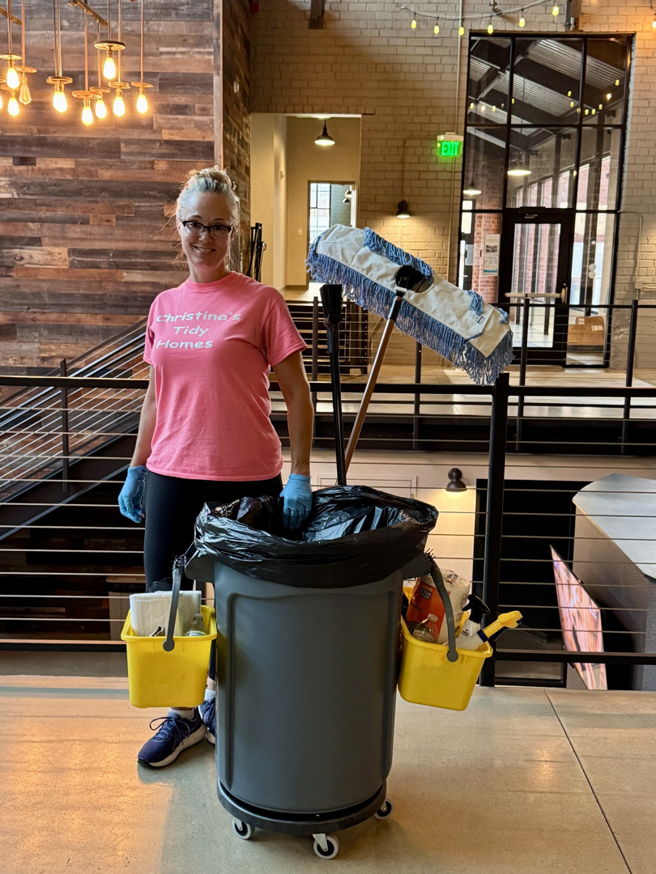 A house cleaner from Christina's Tidy Homes in Canton, OH, standing with a fully equipped cleaning cart.
