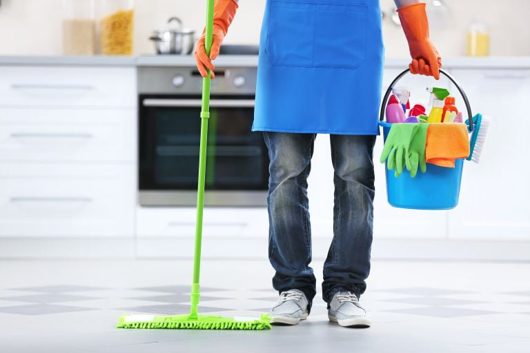 A house cleaner standing in a kitchen with a mop and a bucket of supplies for Price Cleaning Services Omaha in Council Bluffs, IA.
