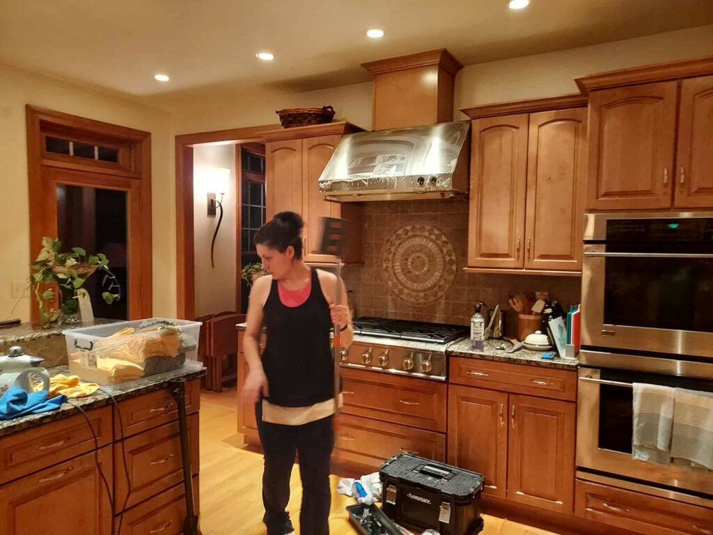 A house cleaner from KDG Decluttering working in a modern kitchen in Manchester, NH.
