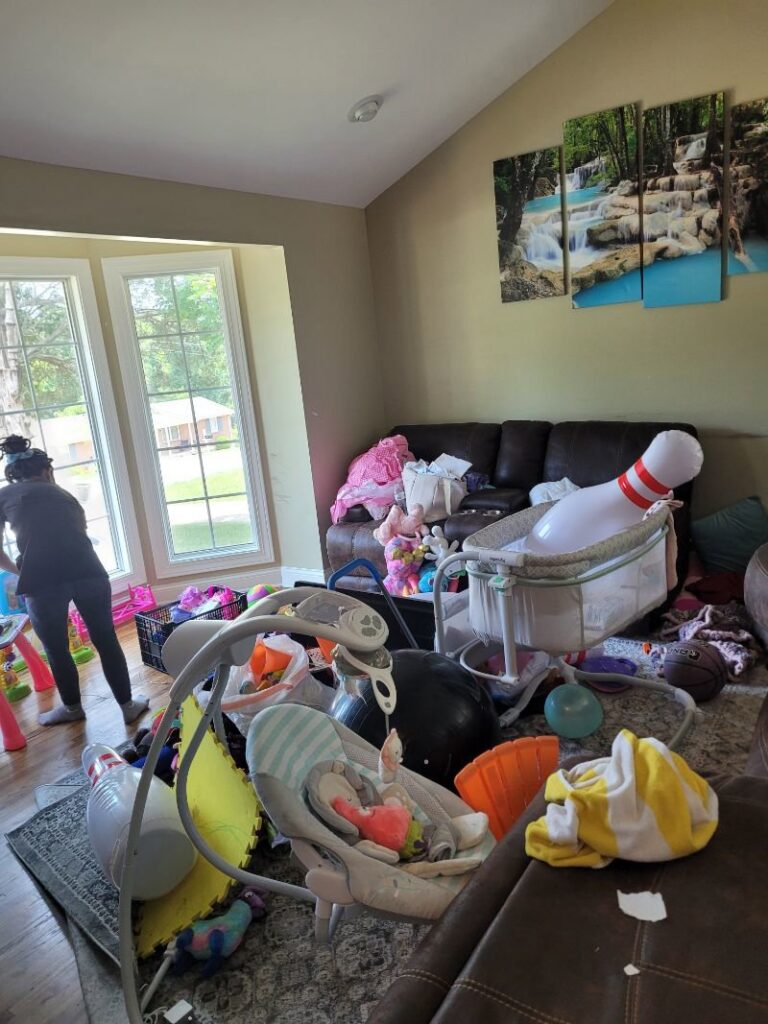 A house cleaner working in a very messy living room, demonstrating the cleaning services provided by Evelyn's Cleaning Services in Huntsville, AL.