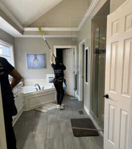 Professional house cleaners dusting a bathroom ceiling at a client's home by Right the 1st Time LLC in Indianapolis, IN