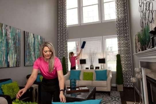 Two house cleaners dusting and tidying a living room for Unity Cleaning in Chicago, IL.