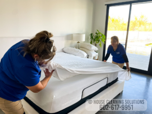 Two house cleaners from House Cleaning Solutions in Mesa, AZ, are meticulously making a bed.