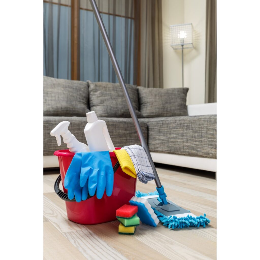 Essential house cleaning supplies, including a mop and bucket, ready in a living room by Harsh's Cleaning Services LLC in Canton, OH.