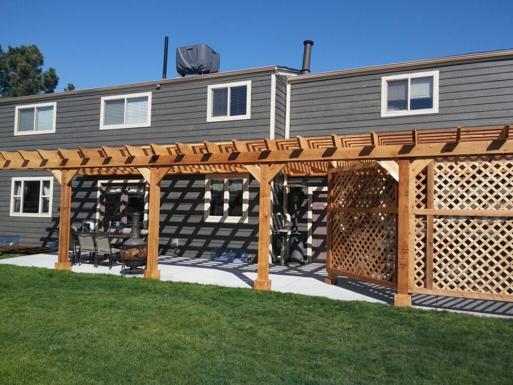 A house with dark gray horizontal siding and a wooden pergola in the backyard, a project by Urban Exteriors LLC in Lakewood, CO.