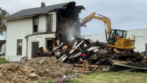 An excavator from Just Take It, LLC. actively demolishing a residential house, creating a pile of debris in Yorba Linda, CA.