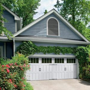 A beautiful home with a double-width white garage door featuring windows and decorative hardware, installed by Overhead Door Company of Salt Lake in Sandy, UT.