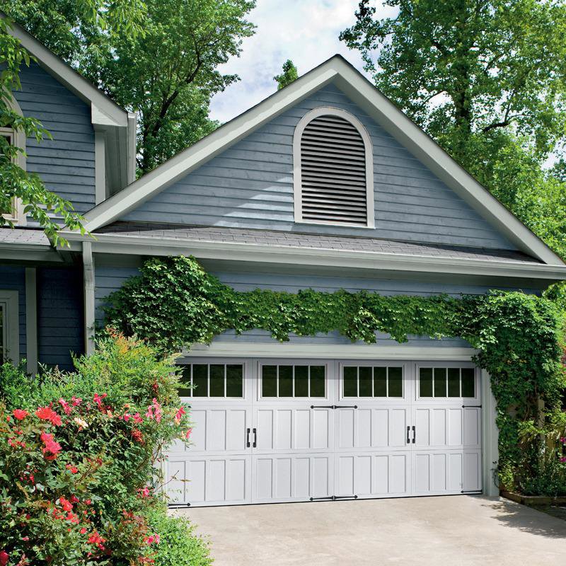 A beautiful home with a double-width white garage door featuring windows and decorative hardware, installed by Overhead Door Company of Salt Lake in Sandy, UT.