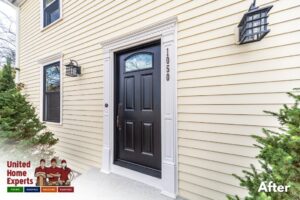 A close-up of a house entrance featuring new light yellow siding and a black door, completed by United Home Experts in Ashland, MA