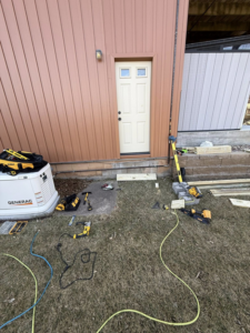 House exterior with brown vertical siding and construction tools on the ground by Peña Industries LLC in Bellevue, NE.