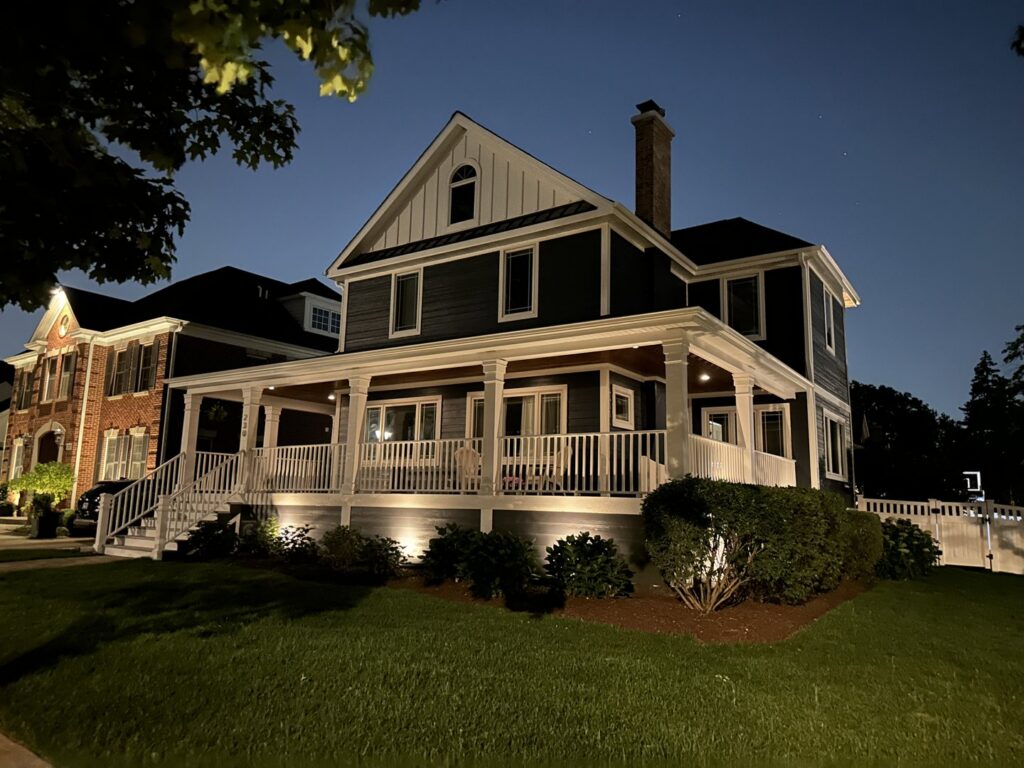 A house exterior at night showcasing dark blue siding by SmardBuild Siding and Exteriors in Naperville, IL