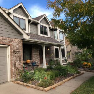 A residential home featuring gray horizontal siding and brick accents, a project by Urban Exteriors LLC in Lakewood, CO.
