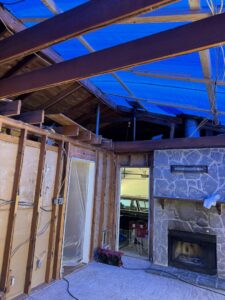 An interior view of a house with exposed studs and a blue tarp on the roof, indicating extensive water damage restoration by KY Water Damage Restoration in Georgetown, KY.