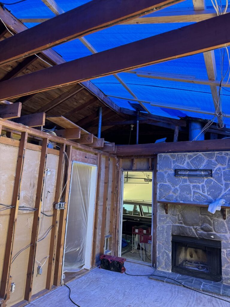 An interior view of a house with exposed studs and a blue tarp on the roof, indicating extensive water damage restoration by KY Water Damage Restoration in Georgetown, KY.