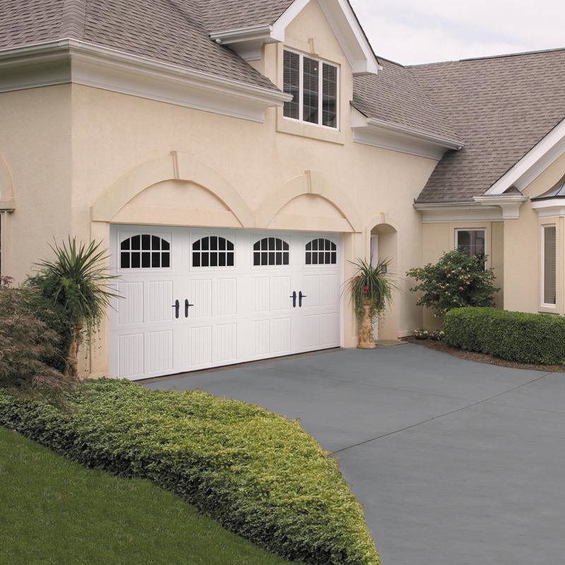 A residential home featuring a large white garage door with elegant arched windows and decorative hardware, installed by Overhead Door Company of Salt Lake in Sandy, UT.
