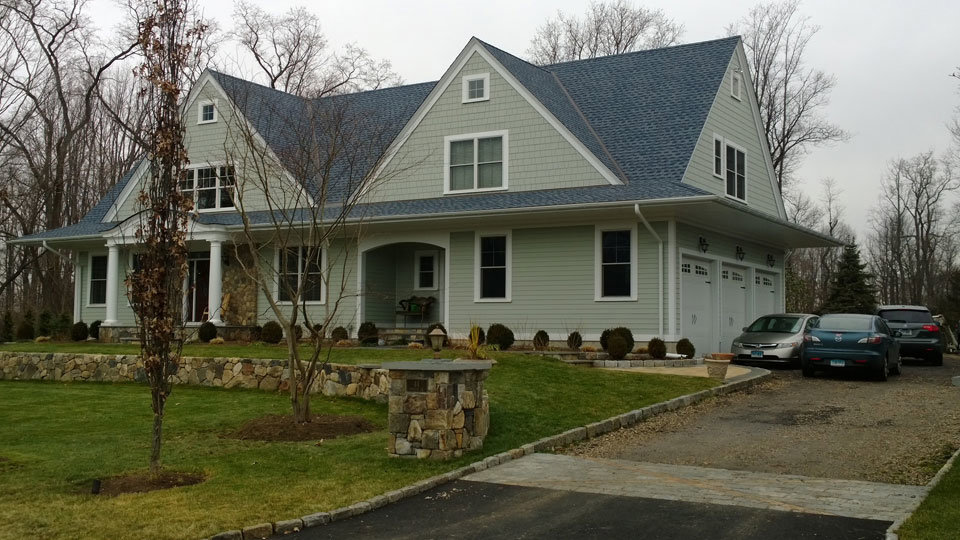 A beautiful house with light green horizontal and shake siding, expertly installed by JM Roofing & Siding in Rogers, AR.