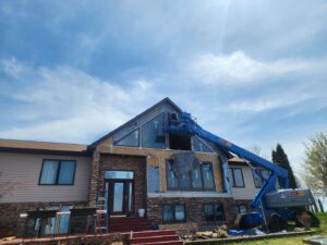 House siding installation in progress with a boom lift, demonstrating work by Murphy Builders- Genesee County in Ossineke, MI.