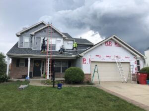 Workers installing new siding and roofing on a residential house by Freeman Exteriors in Danville, IL.