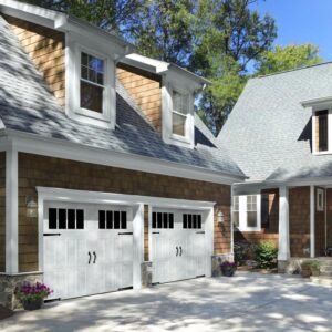 A residential property showcasing two white garage doors with windows and decorative hardware, expertly installed by Overhead Door Company of Salt Lake in Sandy, UT.