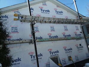 House covered in Tyvek wrap with ladders for siding installation by Capital Siding, Windows & Roofing, Woodbury, MN.