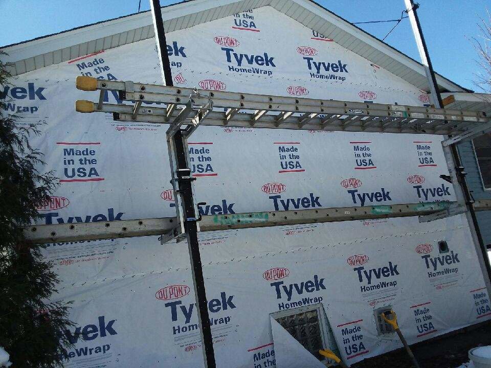 House covered in Tyvek wrap with ladders for siding installation by Capital Siding, Windows & Roofing, Woodbury, MN.