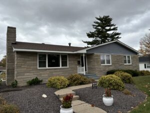 A house featuring blue siding and a stone facade, completed by Freeman Exteriors in Danville, IL.
