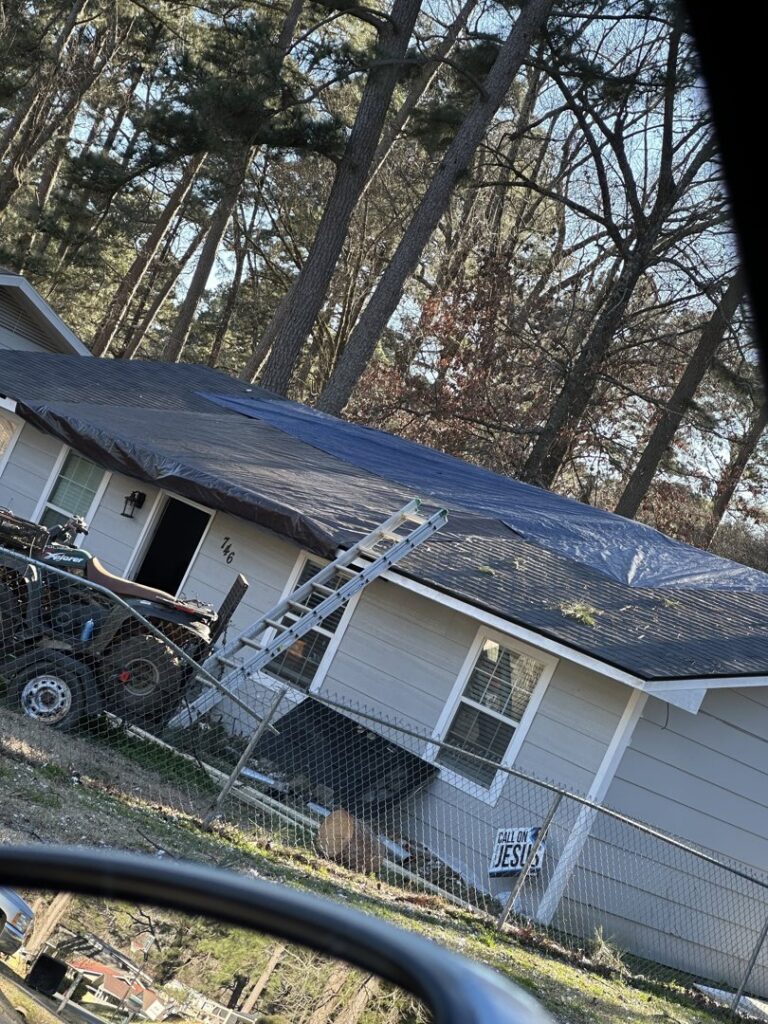 A house with a blue tarp on its roof, indicating storm damage and water intrusion, handled by Restoration Xperts Emergency 24/7 in Deerfield Beach, FL.