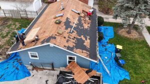 A house with existing brown siding and sections where old siding has been removed, revealing house wrap, by DJ Paz All Siding & Roofing Construction in Iowa City, IA