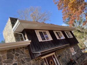 A house featuring dark wood siding and a stone facade, completed by J&J Rivera Roofing and Supply Co in Old Saybrook, CT