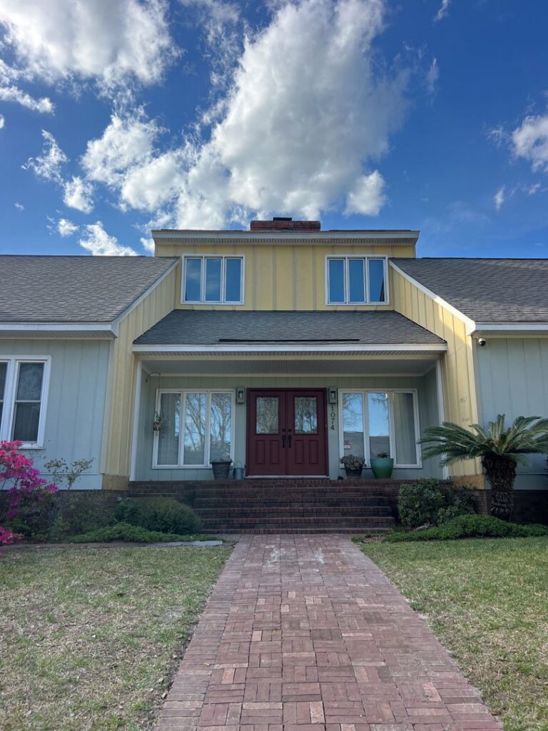 Front view of a house featuring new yellow and light blue siding installed by Powell Roofing in Ladson, SC.