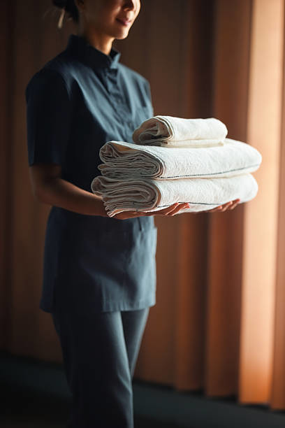 A professional housekeeper holding a stack of neatly folded white towels for Premier Uptown Clean in Charlotte, NC