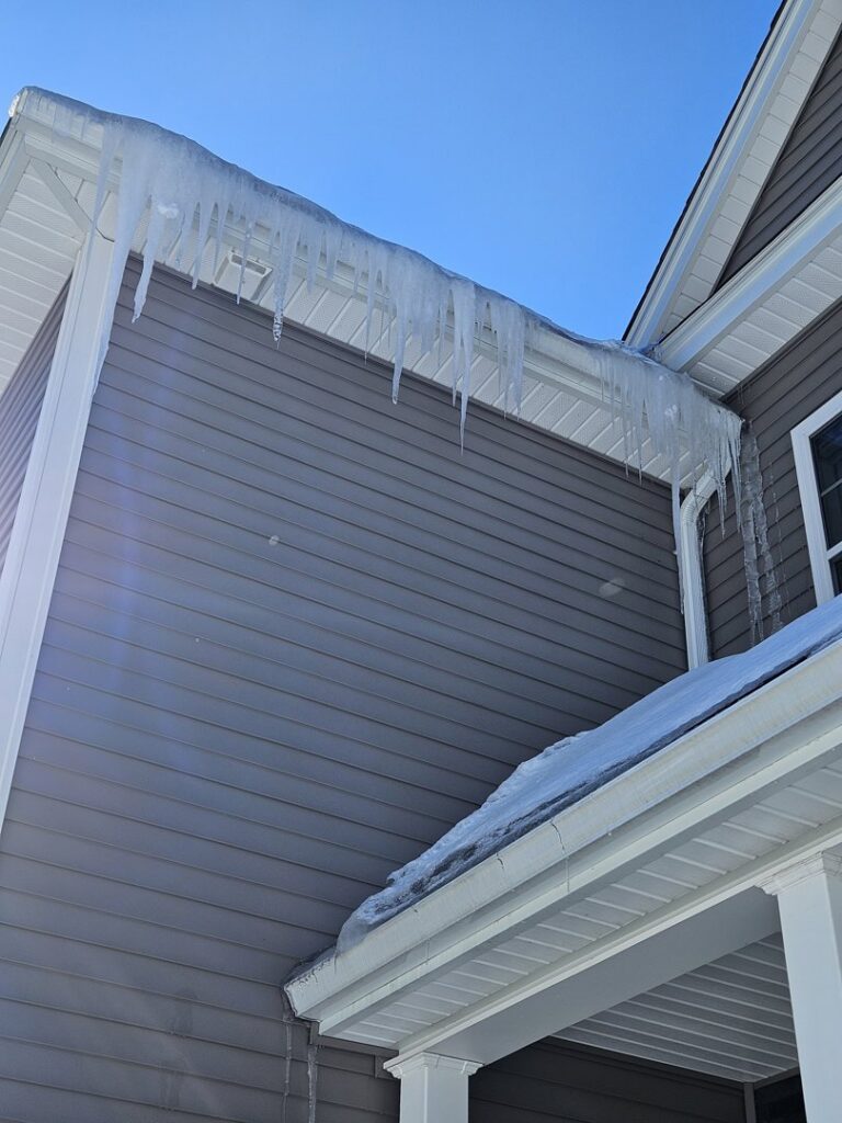 Large icicles hanging from a house gutter, indicating a need for ice dam removal by Senco Home Services in Lynn, MA.