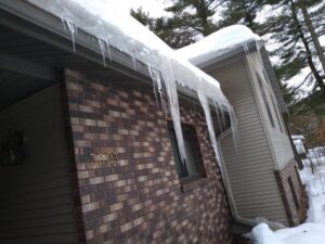 Large icicles hanging from house gutters, a sign of potential ice damming and water damage, handled by Local Clean Up Specialists in Green Bay, WI.