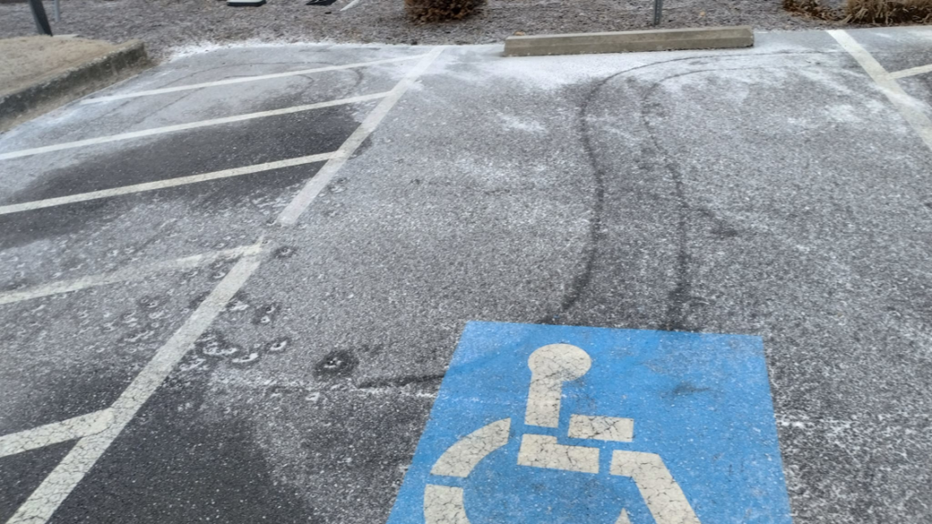 An icy parking lot with a handicap spot, ready for snow and ice removal by Kickin Grass Lawncare LLC in Springdale, AR.