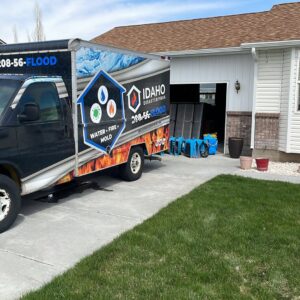 An Idaho Disaster Pros branded truck parked outside a home with water damage drying equipment visible in Idaho Falls, ID.