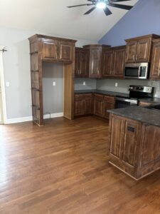 An immaculate residential kitchen with dark wood cabinets and gleaming floors, cleaned by Uniquely Clean Professional Services in Kansas City, MO.