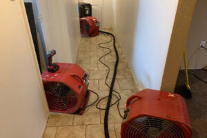 Industrial air movers and drying equipment set up in a hallway to dry water-damaged areas by Local Clean Up Specialists in Green Bay, WI.