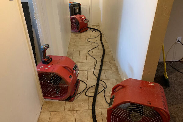 Industrial air movers and drying equipment set up in a hallway to dry water-damaged areas by Local Clean Up Specialists in Green Bay, WI.
