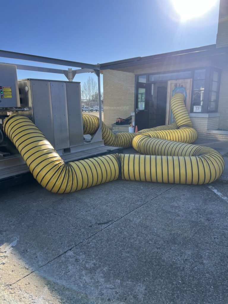 Industrial yellow drying ducts extending from equipment into a building for water damage restoration by Express Restoration in Edmond, OK.