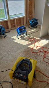 Industrial fans and dehumidifiers drying a room with exposed studs after water damage by Guardian Angel Restoration in Noblesville, IN