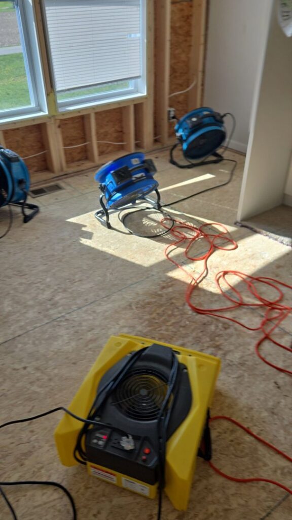 Industrial fans and dehumidifiers drying a room with exposed studs after water damage by Guardian Angel Restoration in Noblesville, IN