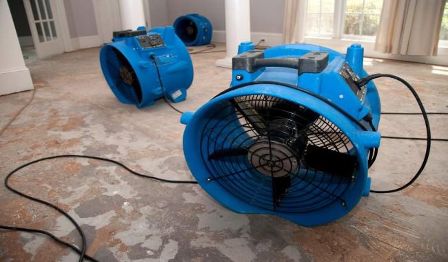 Industrial fans drying a water-damaged concrete floor during restoration by Emergency Response Services Inc. in Warren, MI