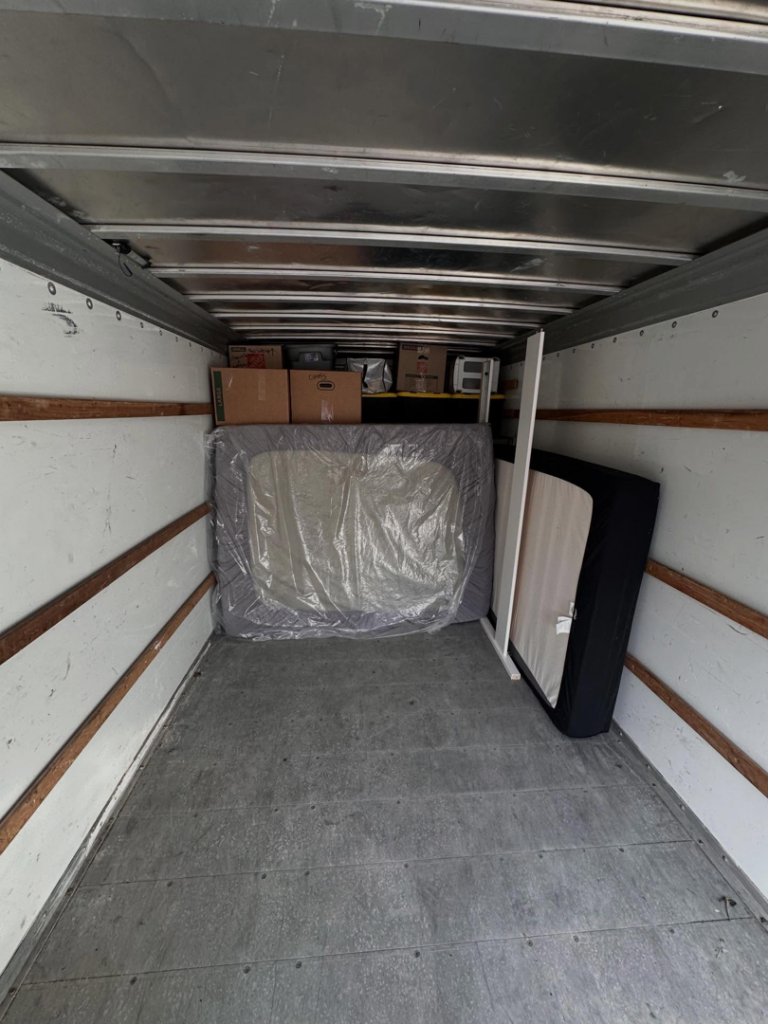 Inside a moving truck partially loaded with a mattress and boxes by By Any Means Movers in Rochester, NY.